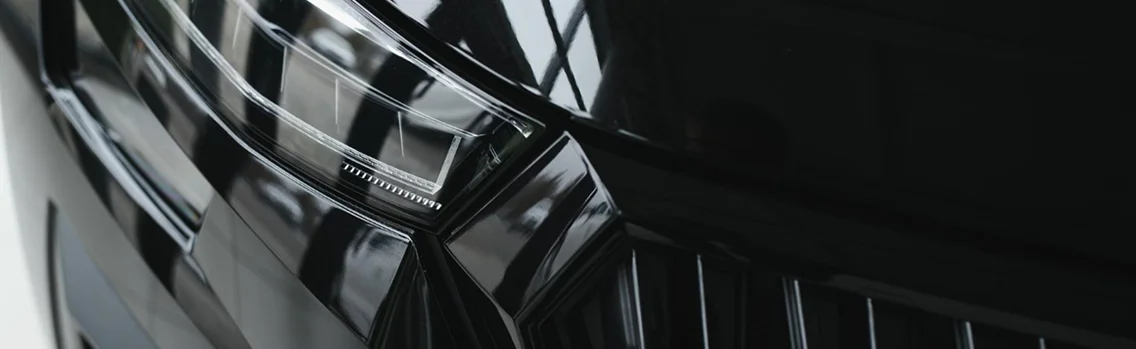 Detalhe de um farol de LED preto moderno com design elegante, acabamento brilhante e detalhes automotivos de alta qualidade.